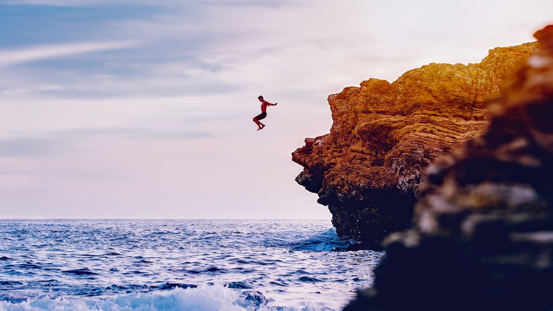 A person leaping from a sea cliff into the ocean